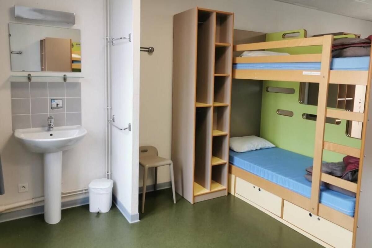A room with bunk beds, a sink, and a mirror.