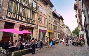 A cobblestone street lined with traditional half-timbered buildings, outdoor seating for cafes, and pedestrians. - Auberge de Jeunesse HI Rouen (Rouen)
