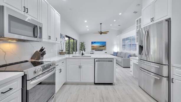 A modern kitchen with white cabinetry, stainless steel appliances, and a central island.