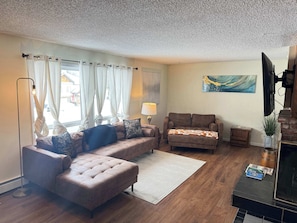 A living room with a sofa, armchair, and a flat-screen TV.