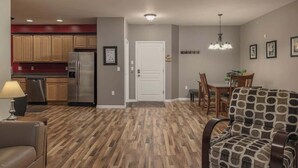 Una cocina moderna con armarios de madera, un refrigerador de acero inoxidable y una zona de comedor con una mesa y sillas de madera.