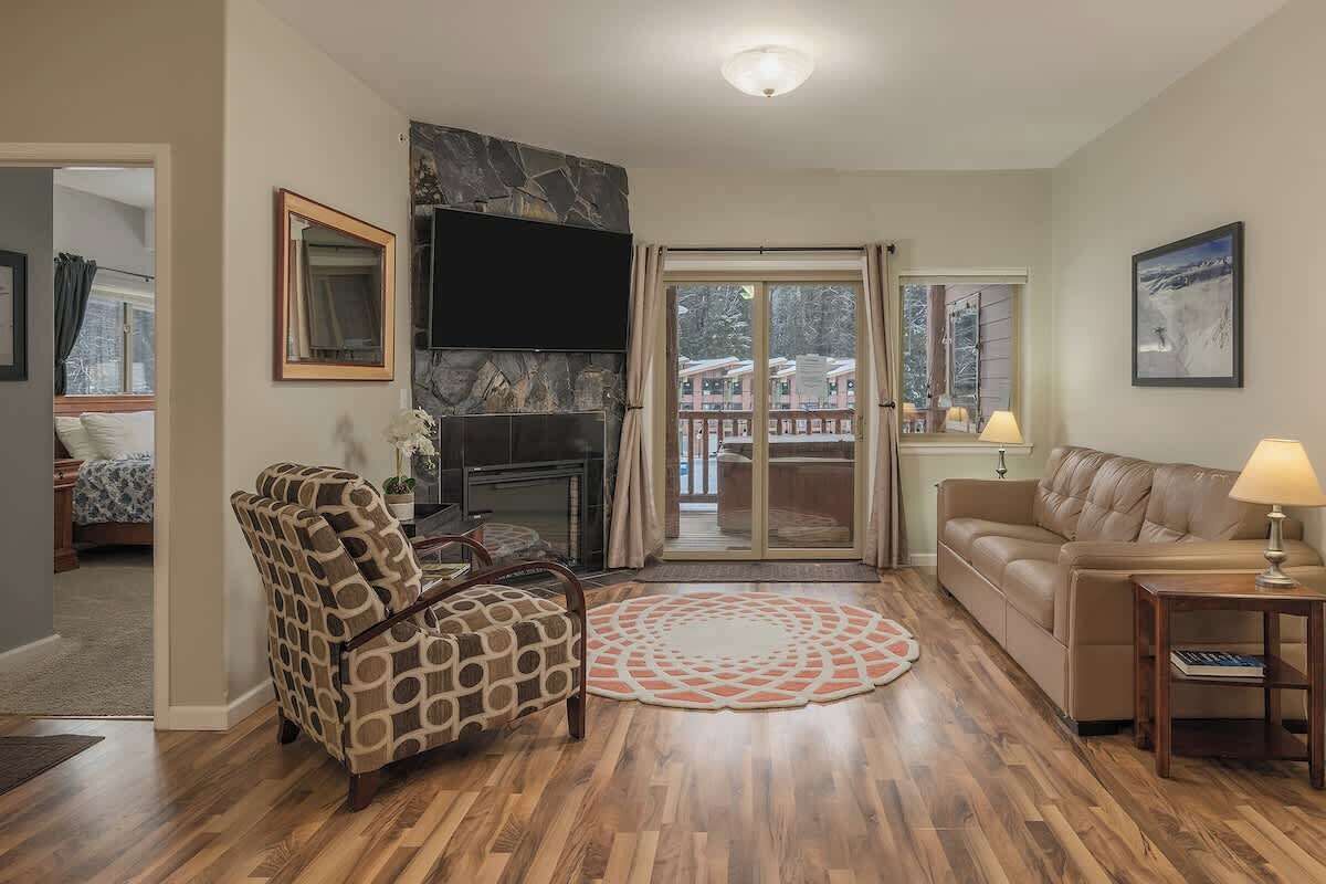 A living room with a fireplace, a patterned armchair, a sofa, and a coffee table.