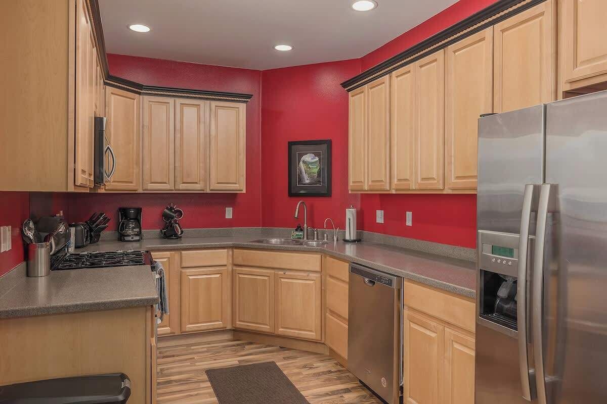 A kitchen with wooden cabinets, a stainless steel refrigerator, and a dishwasher.