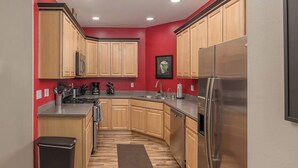 Una cocina compacta con armarios de madera, un refrigerador de acero inoxidable y un microondas integrado.