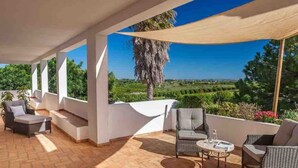 Un espacio al aire libre cubierto con asientos y vista a un viñedo.