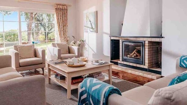 Una sala de estar con chimenea, asientos cómodos y vistas al exterior.