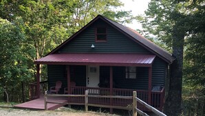 A rustic cabin with a porch, a small window, and a door.