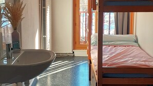 A room with a bunk bed, a sink, a window, and a radiator.