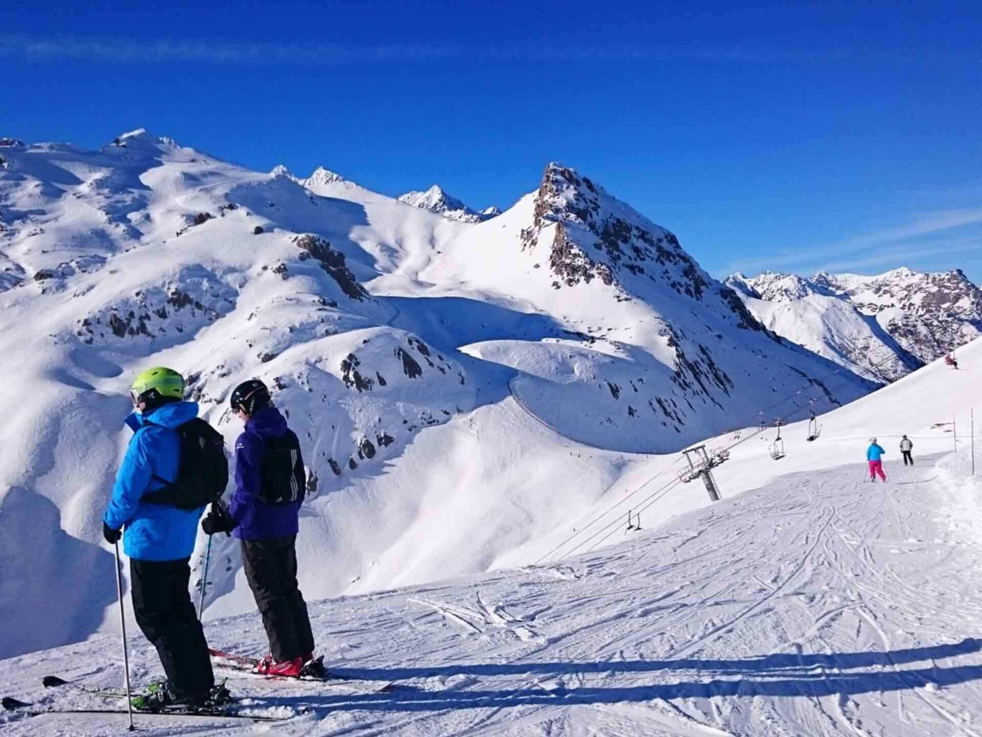 A snowy mountain landscape with skiers and a ski lift.