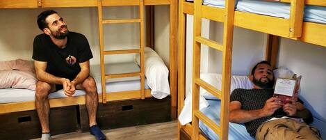 Un dormitorio con literas, suelo de madera y pared blanca.