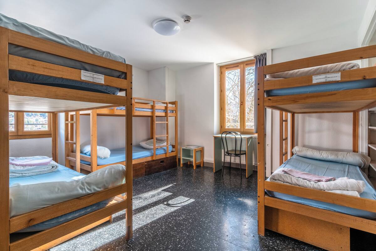 Ein Schlafsaalzimmer mit Etagenbetten, einem Schreibtisch und einem Stuhl.