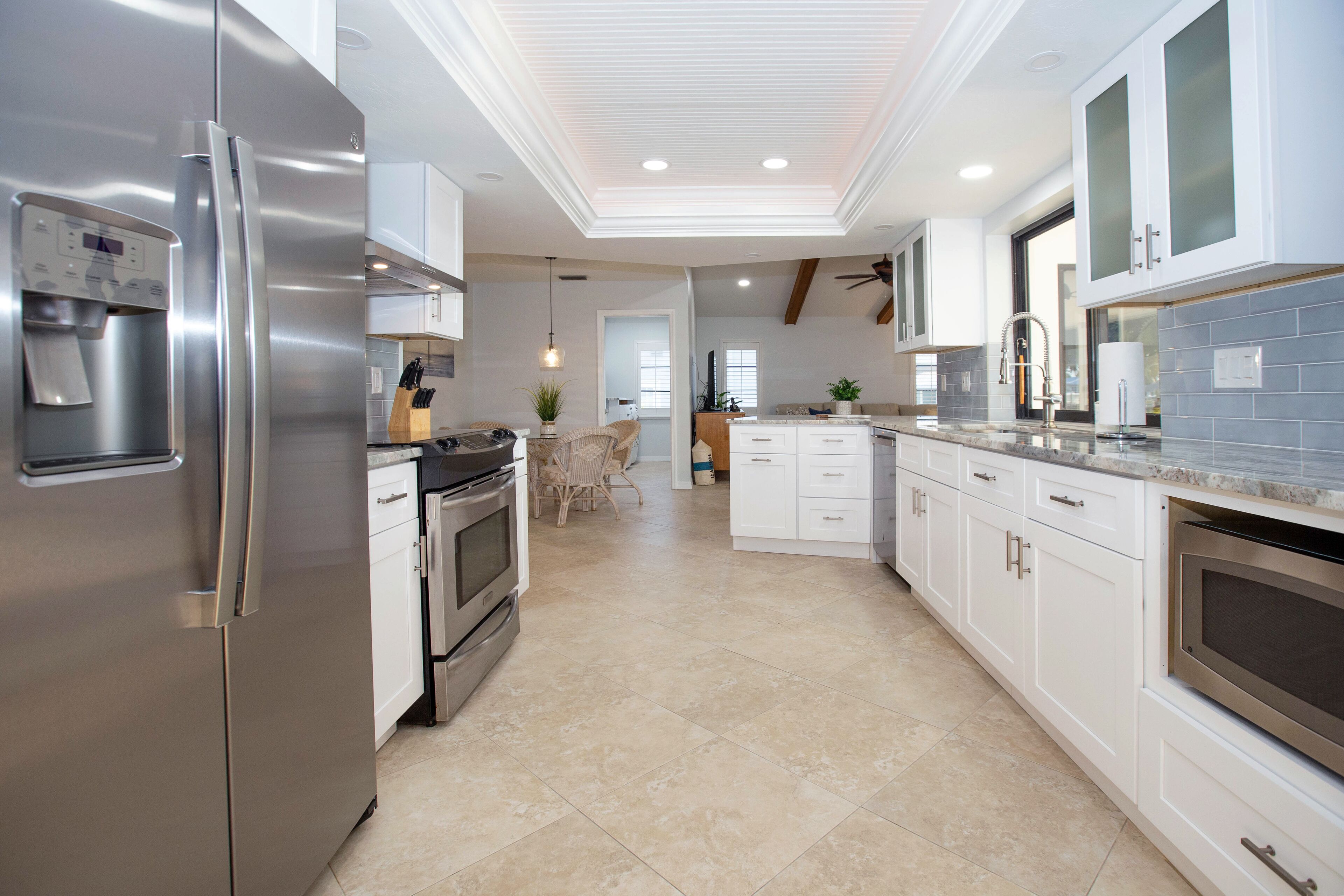 A modern kitchen with stainless steel appliances, white cabinetry, and a tiled floor.