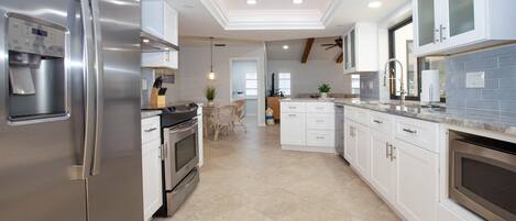 A modern kitchen with stainless steel appliances, white cabinetry, and a tiled floor.