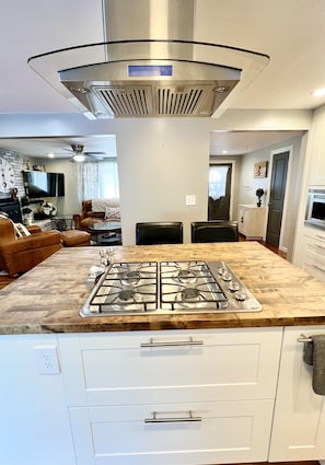 A modern kitchen with a gas stove, white cabinets, and a glass range hood.