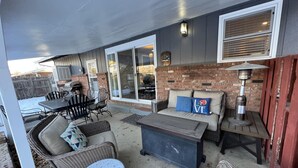 Un patio al aire libre con comedor, asientos y un calentador.