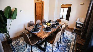 Un coin repas avec une table en bois dressée pour six personnes, entourée de chaises.