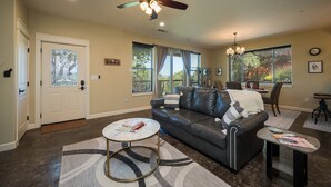 A living room with a dark leather sofa, a round coffee table, and a ceiling fan. - Z Ranch - Modern French Country Style With Stunning Views (Atascadero)