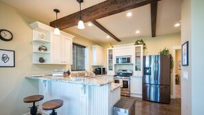 A modern kitchen with a central island, stainless steel appliances, and pendant lighting. - Z Ranch - Modern French Country Style With Stunning Views (Atascadero)
