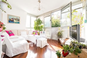 Relax in this stylish room with a sofa, armchair, and table, offering a view of lush greenery.