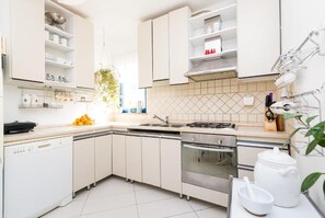 Modern kitchen with white cabinetry, stainless steel sink, gas stove, dishwasher, and oven.