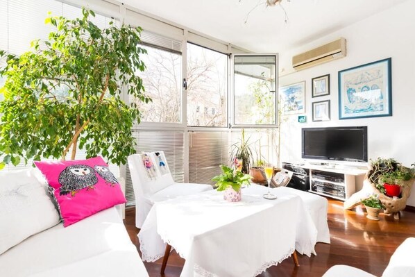 Relax in this inviting living room with a sofa, flat-screen TV, and lush greenery.