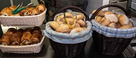 Three wicker baskets filled with various types of bread on a kitchen counter.