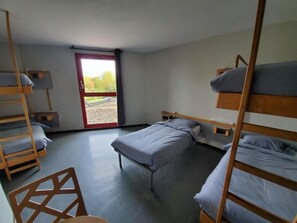 A dormitory room with bunk beds, a single bed, a chair, and a door leading outside. - Auberge de Jeunesse HI Strasbourg (Strasbourg)