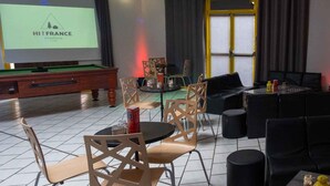 A room with a pool table, a projector screen displaying "HI! FRANCE Strasbourg", and a billiards setup.