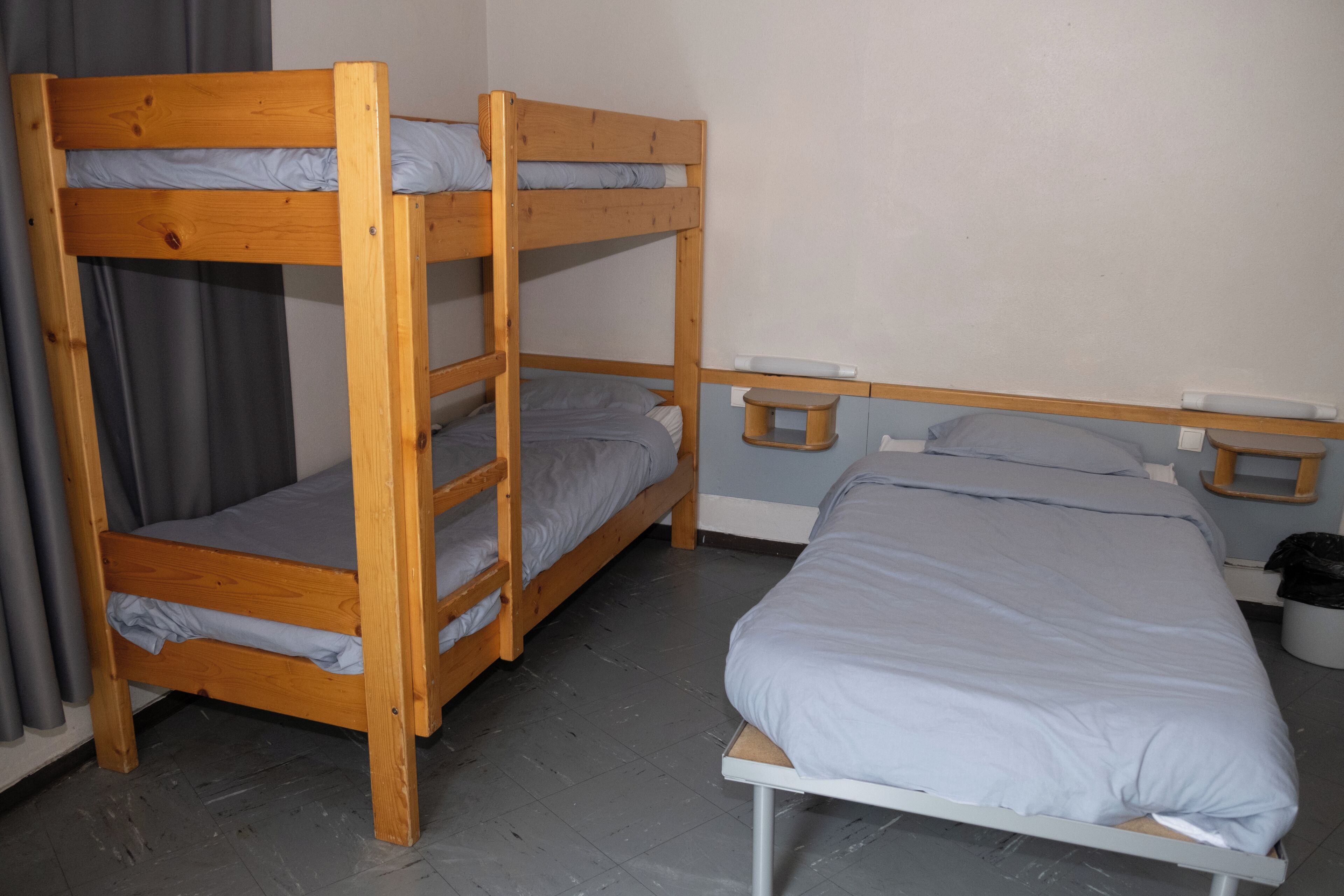 A bunk bed room with a single bed and a wooden bunk bed.