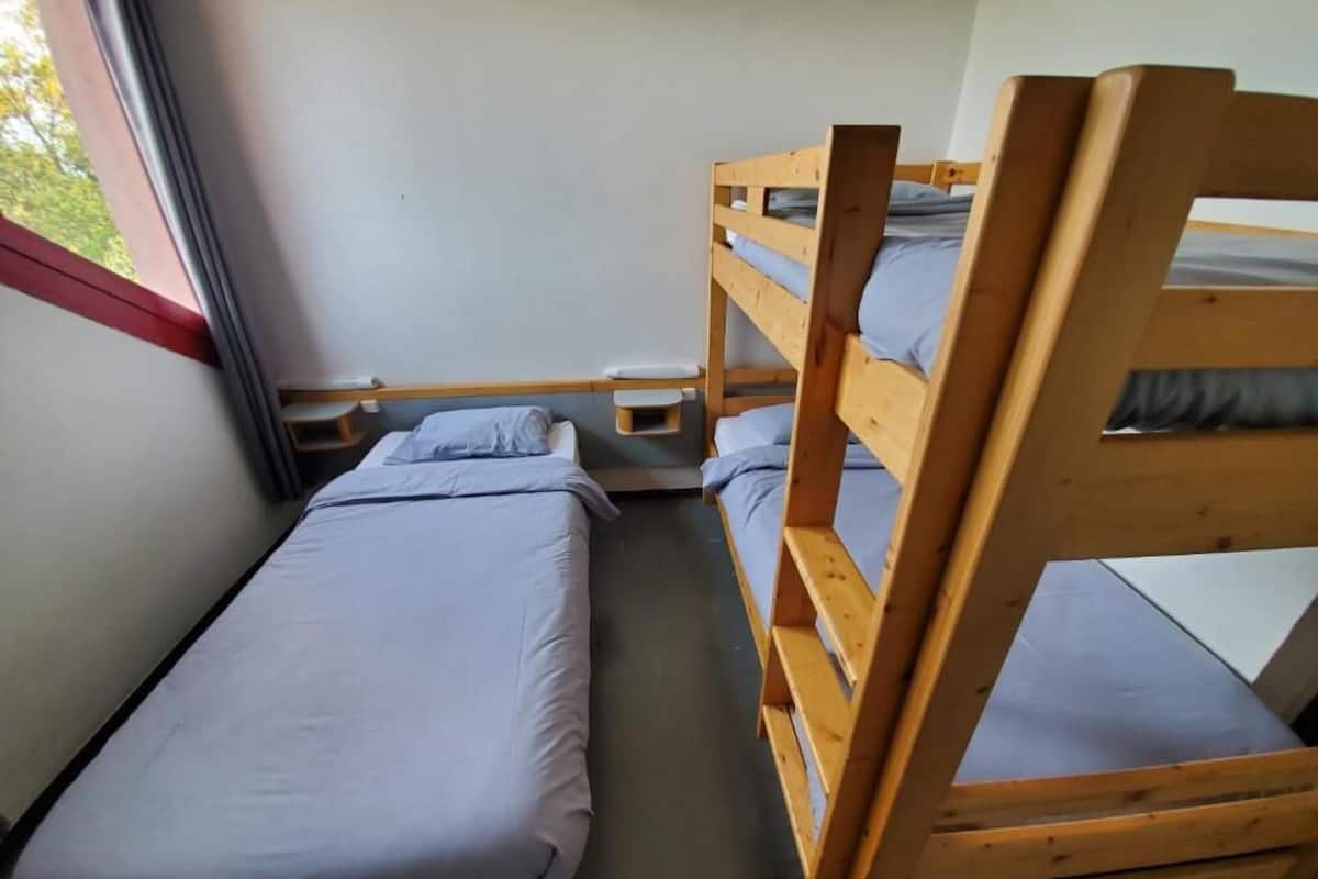 A small, compact room with two bunk beds and a single bed.
