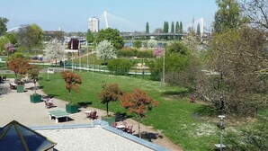A park with picnic tables, a playground, and a bridge in the background.