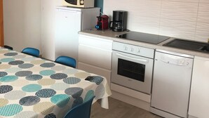 Ett kompakt kök med vita skåp, en mikrovågsugn, en kaffebryggare och en diskmaskin.