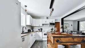 A modern kitchen with white cabinets, a wooden table, and a large window. - Chalet with waterfront, Spa and magnificent view of a regional park (Chertsey)