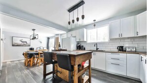 A modern kitchen with white cabinets, a wooden island, and pendant lighting. - Chalet with waterfront, Spa and magnificent view of a regional park (Chertsey)