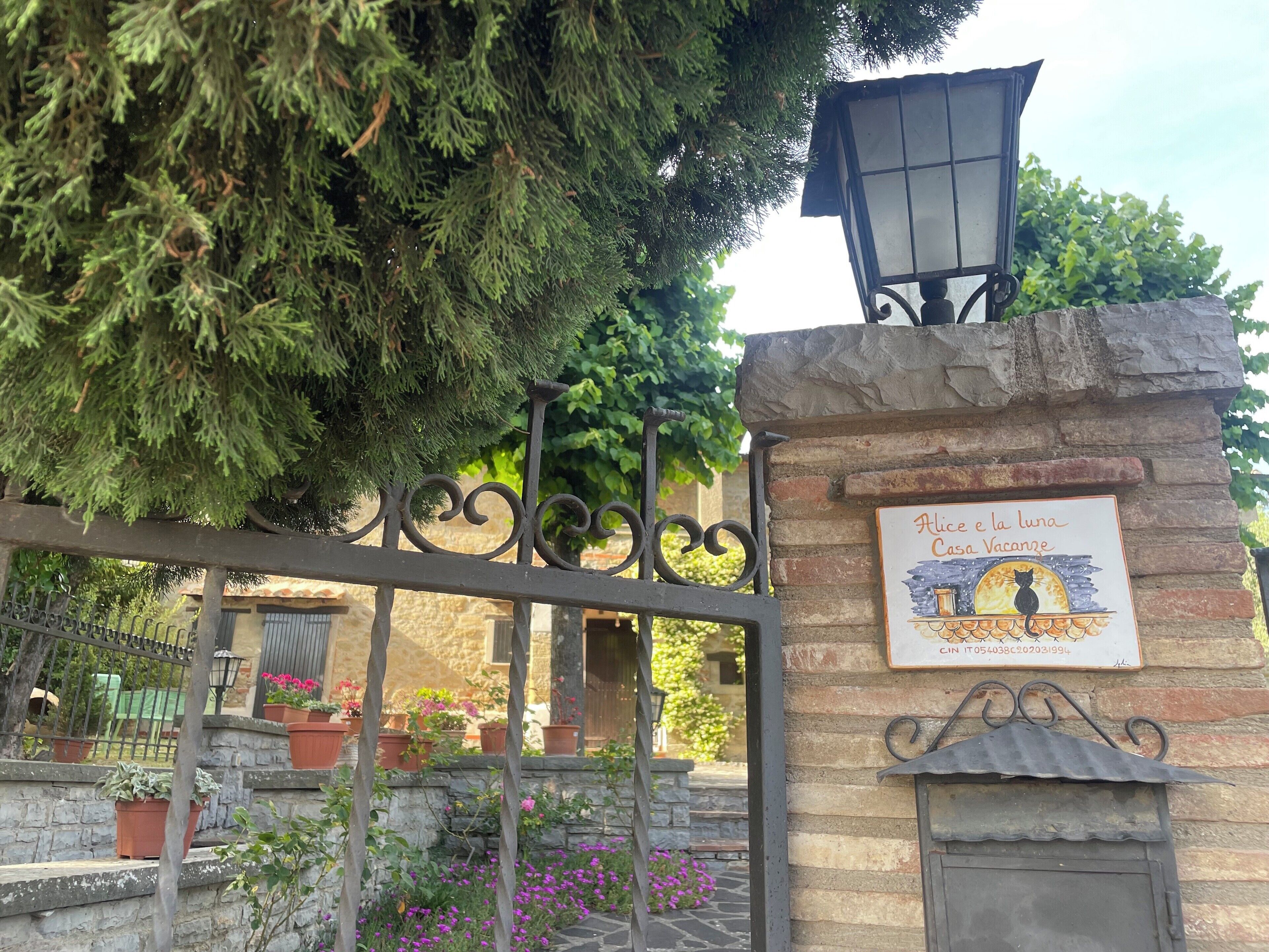 Une porte en pierre surmontée d’une enseigne indiquant « Alice e la luna Casa Vacanze » et d’une lampe.