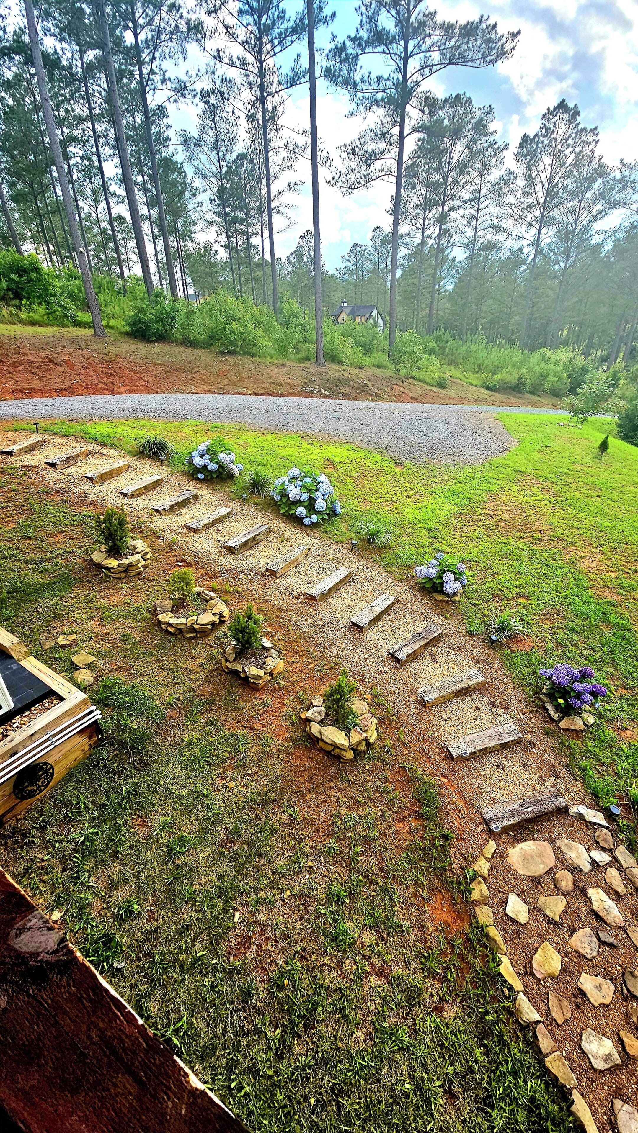 A landscaped garden with a gravel path, potted plants, and a wooden bench.