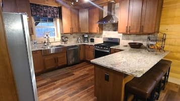 A kitchen with wooden cabinets, a stainless steel refrigerator, a built-in oven, and a granite countertop.