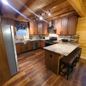 A kitchen with wooden cabinets, a stainless steel refrigerator, a built-in oven, and a granite countertop.