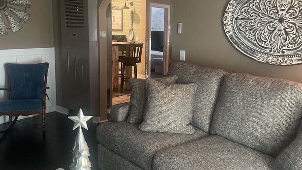A living room with a grey sofa, a decorative wall piece, and a star-shaped table decoration. - The Pink House - Charming, fully renovated, quiet getaway (Wellfleet)