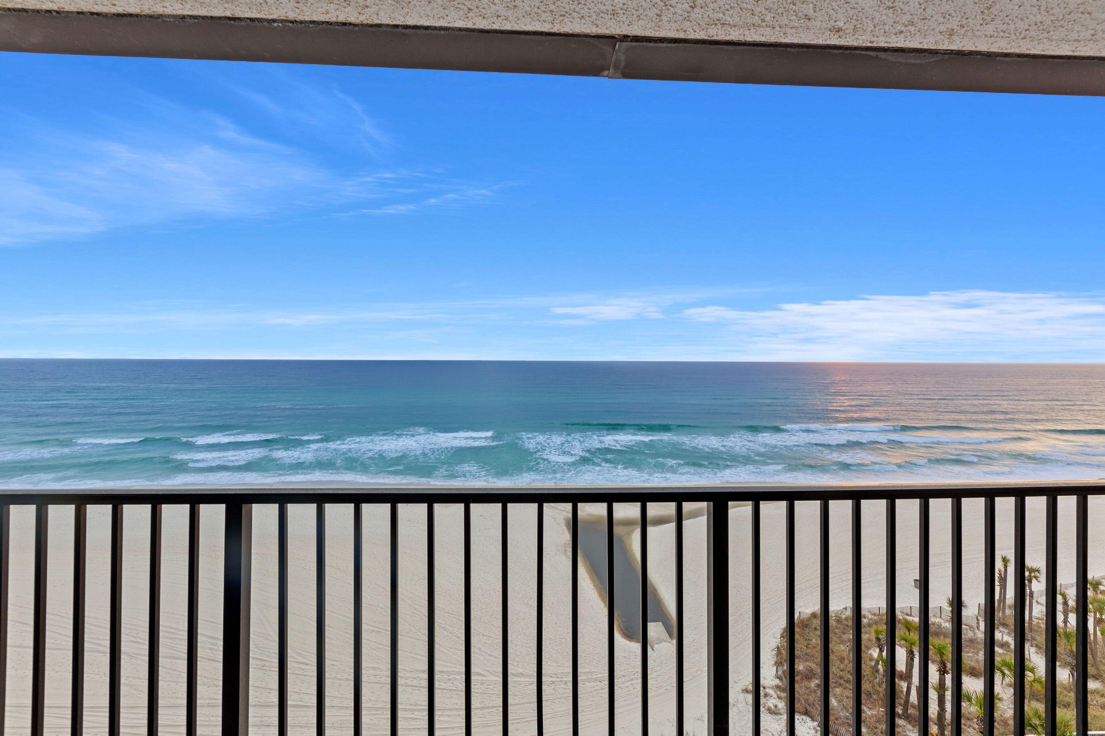 Een balkon met uitzicht op de oceaan en het strand.
