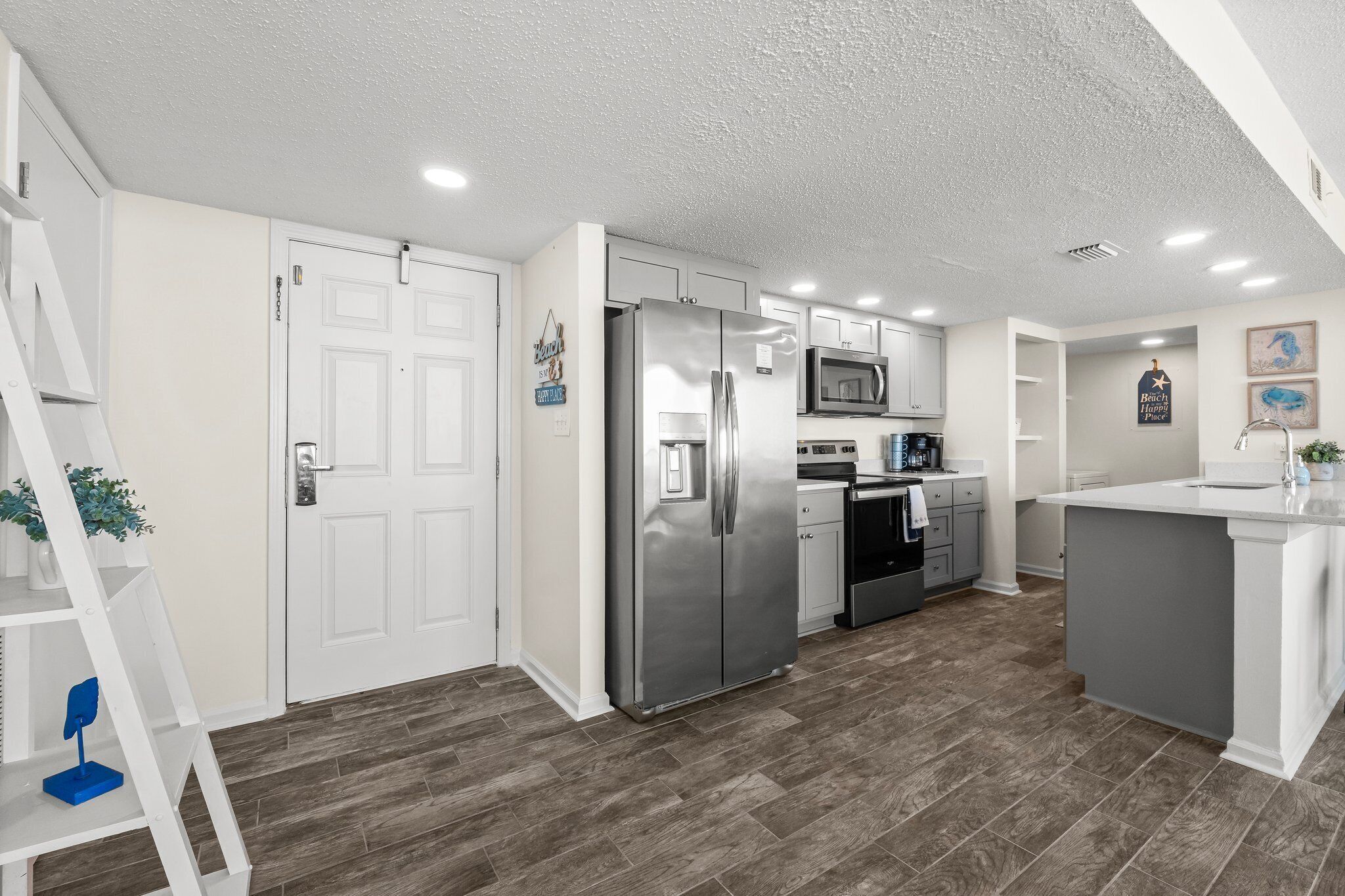 A modern kitchen with white cabinetry, stainless steel appliances, and a grey island.