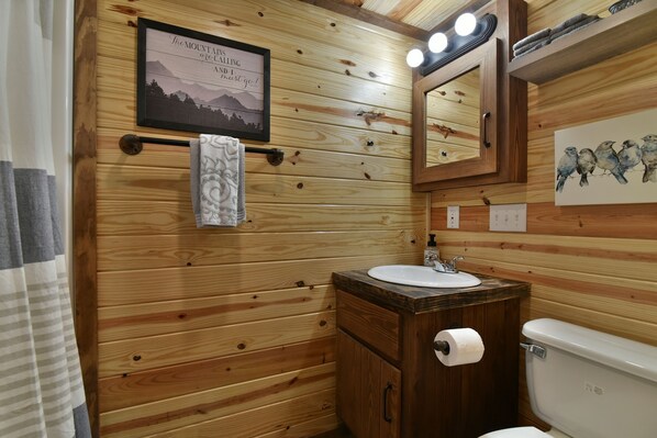 A wooden cabin bathroom with a wooden vanity, sink, and toilet.