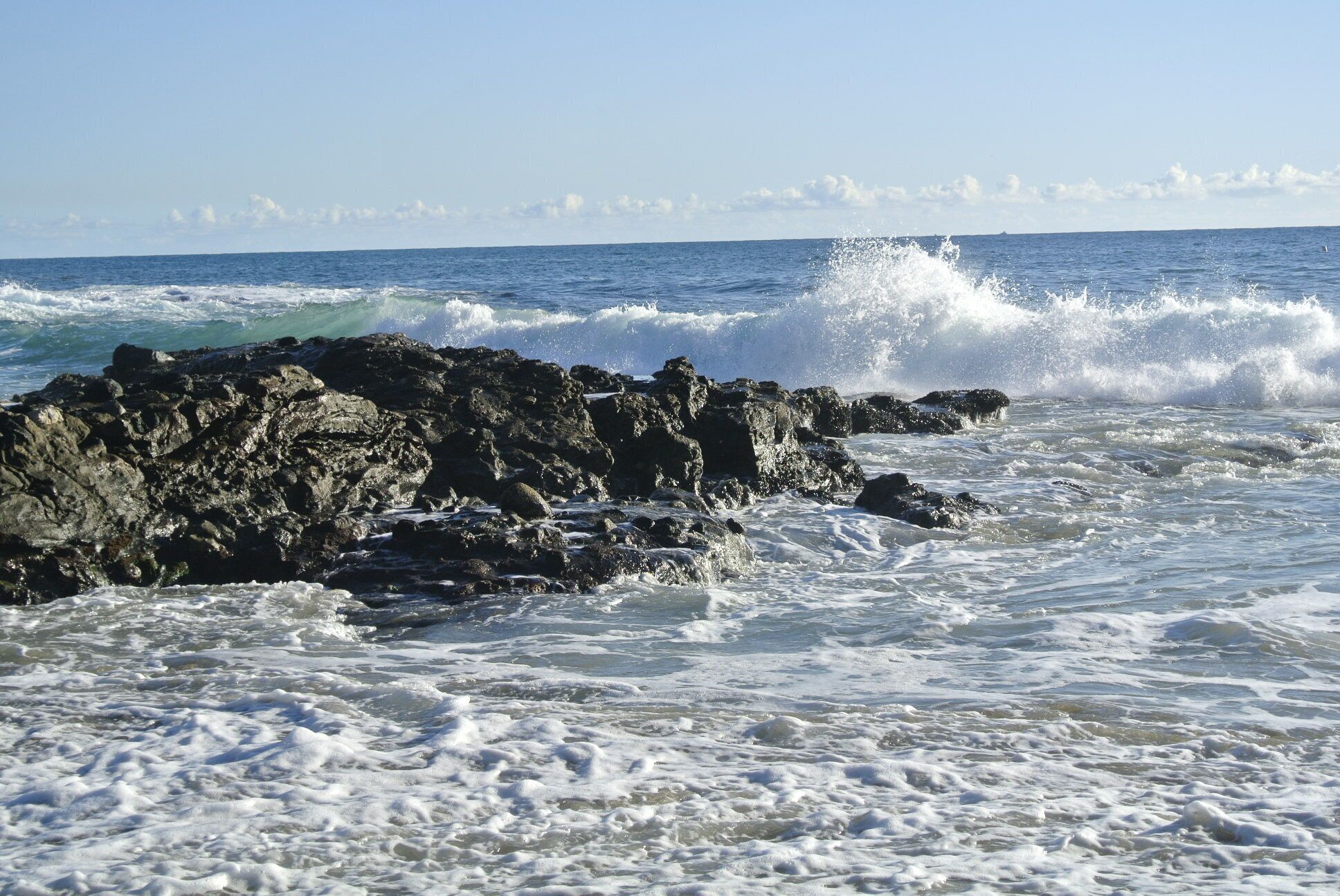 Una costa rocosa con olas rompiendo contra las rocas.