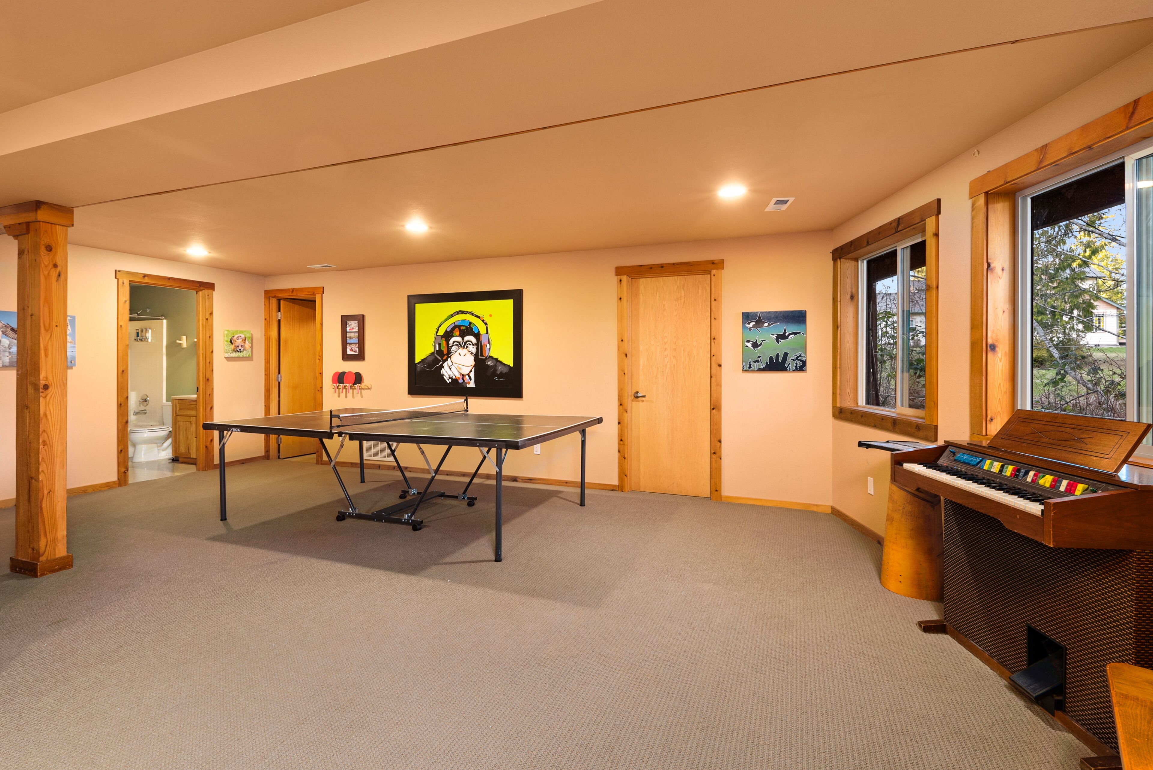 Une pièce avec une table de ping-pong, un piano et des œuvres d’art accrochées aux murs.