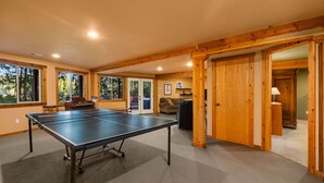 A spacious room with a ping pong table, wooden beams, large windows, and a cozy seating area. - Enchanting Lindal Waterfront Cabin (Shelton)