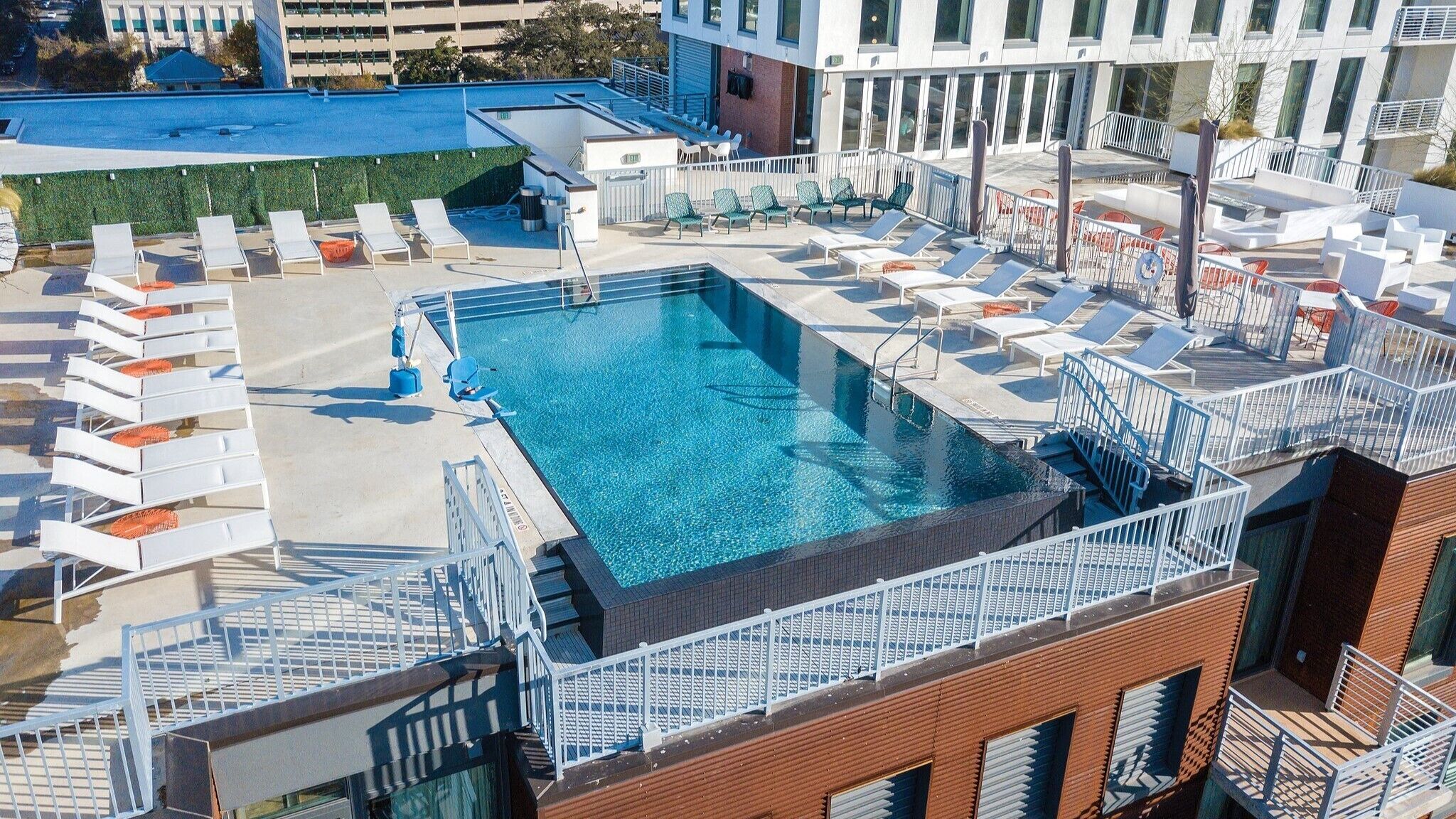 A rooftop pool with multiple lounge chairs and a clear blue pool.