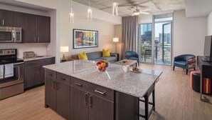 A modern kitchen with a granite island, stainless steel appliances, and a dining area with a sofa and chairs.