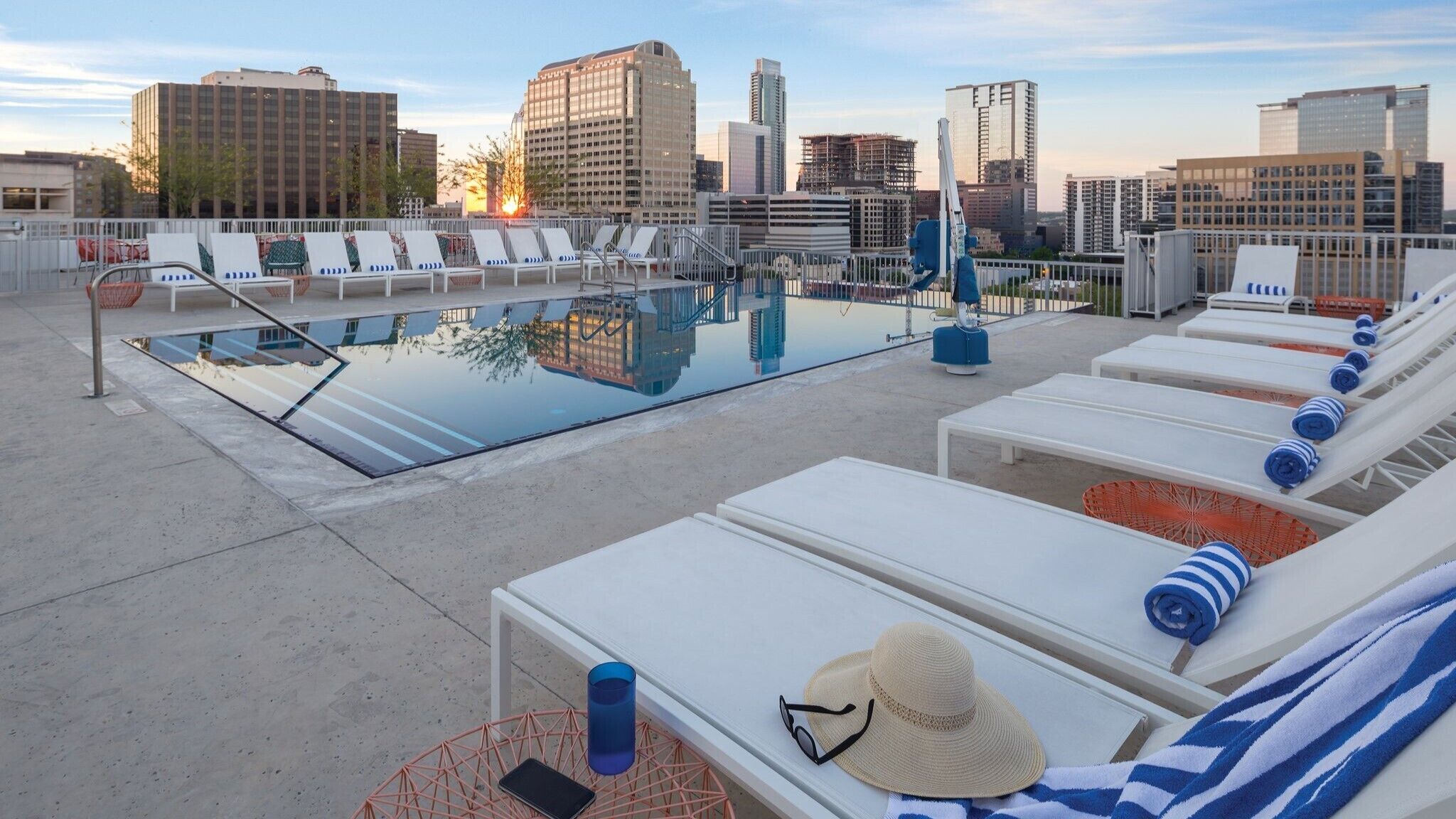Zona de piscina en la azotea con sillas de descanso y vista panorámica de la ciudad.