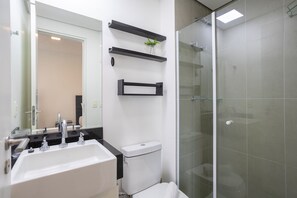 A modern bathroom with a white sink, a toilet, and a glass-enclosed shower.