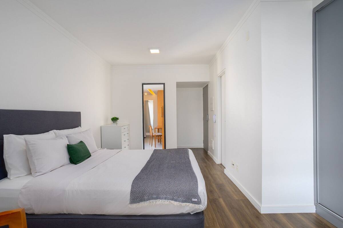 Habitación de hotel moderna con una cama grande, un escritorio pequeño y vistas al pasillo.
